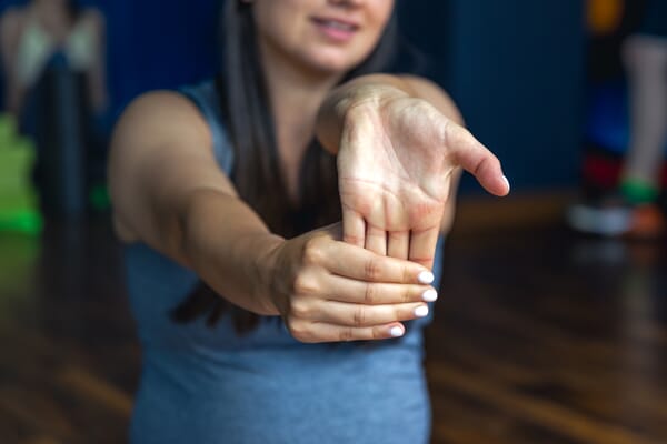 femme réalisant un étirement du poignet pour les douleurs